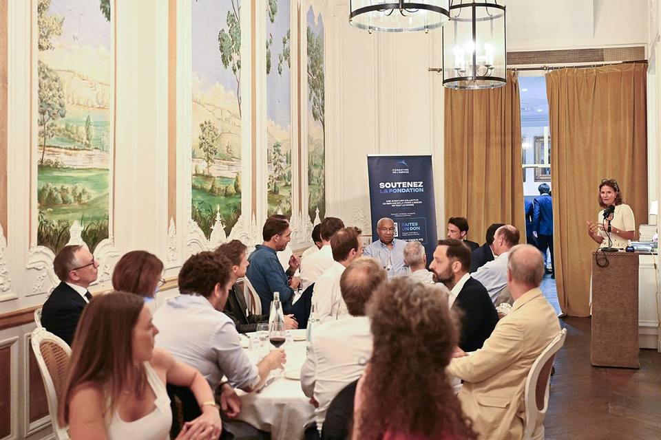 Salon aux panneaux peints de l'Hôtel Alfred Sommier, convives réunis autour de la table pendant la prise de parole