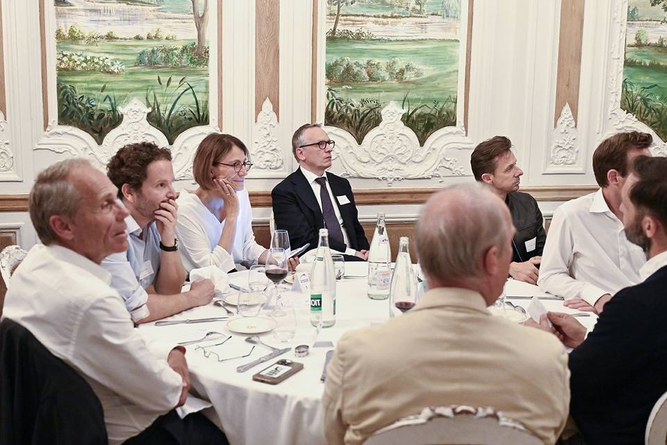 Convives autour d'une table ronde, écoutant la prise de parole