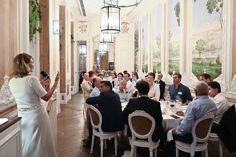 Vue de la salle en enfilade, une intervenante au pupitre face aux convives attablés
