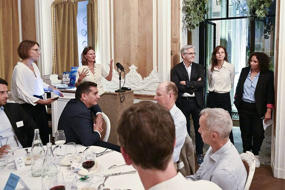 Échanges debout près du pupitre à la fin de la prise de parole, marque-place « Sciences & Éducation » au premier plan