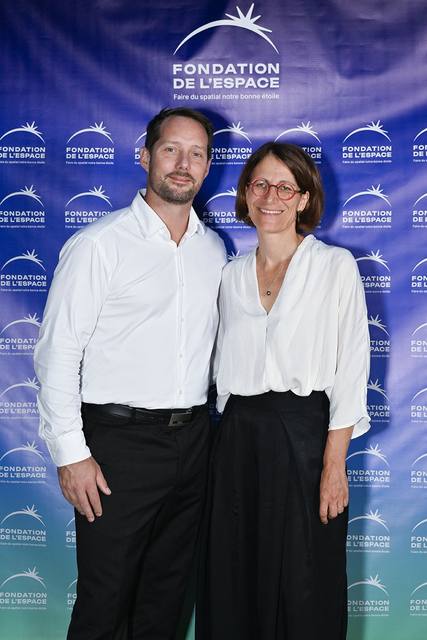 Portrait vertical de deux convives devant le mur aux logos de la Fondation