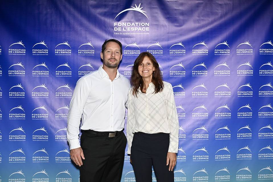 Deux convives posant devant le mur aux logos de la Fondation