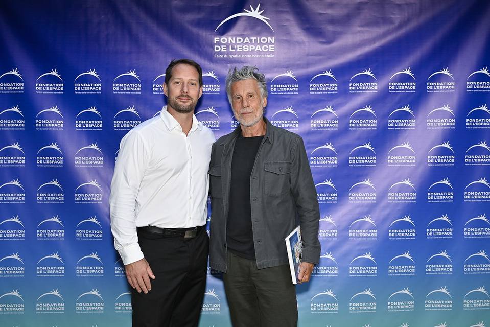 Deux convives posant devant le mur aux logos de la Fondation