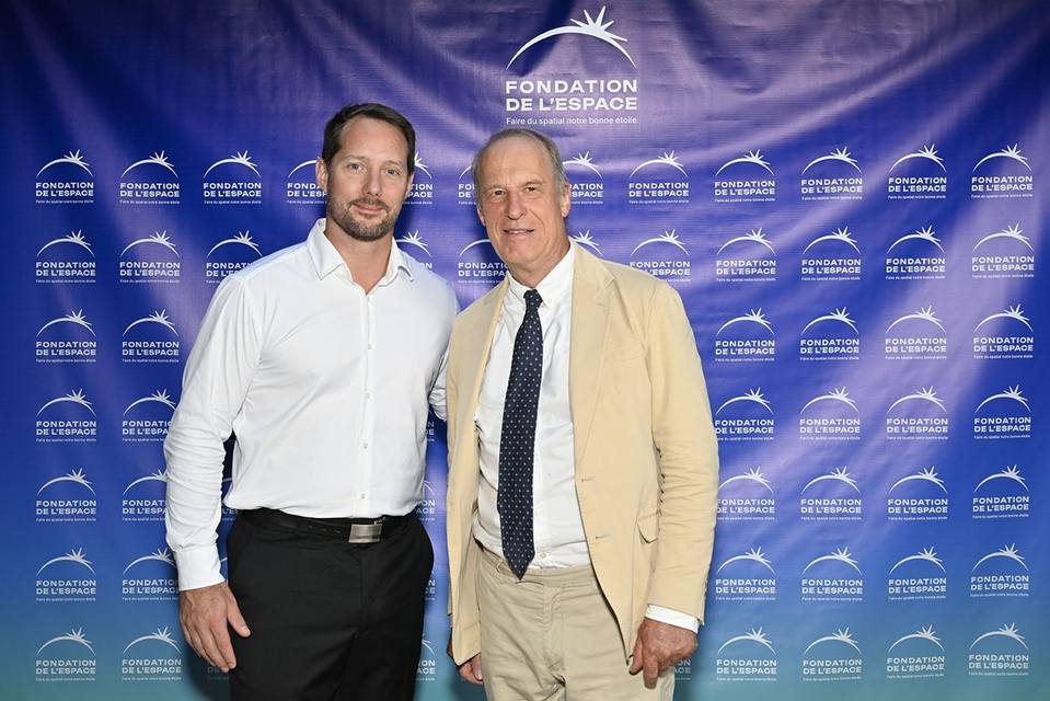 Deux convives posant devant le mur aux logos de la Fondation