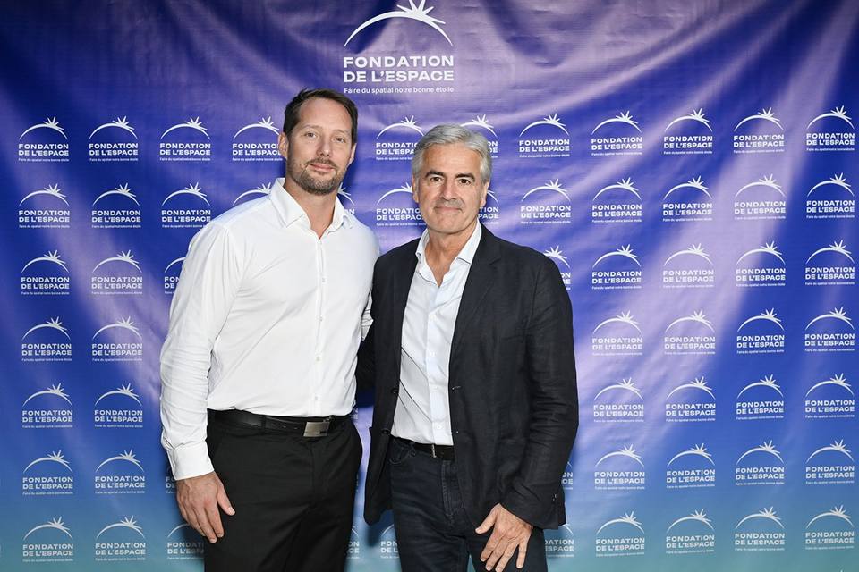 Deux convives en veste sombre devant le mur aux logos de la Fondation