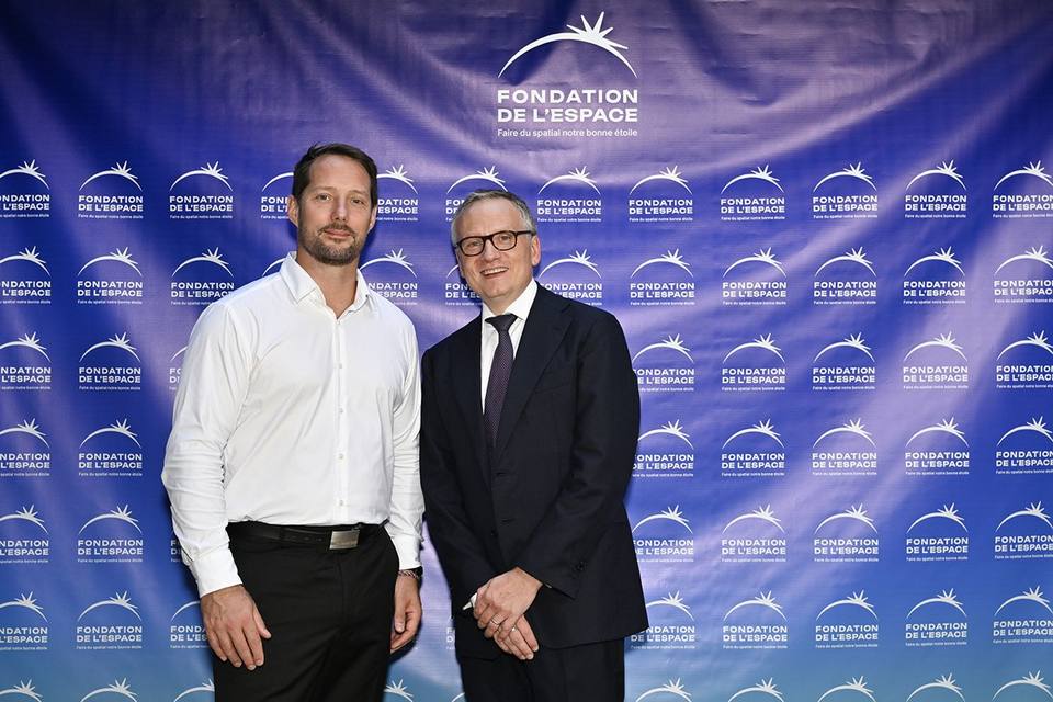 Deux convives posant devant le mur aux logos de la Fondation