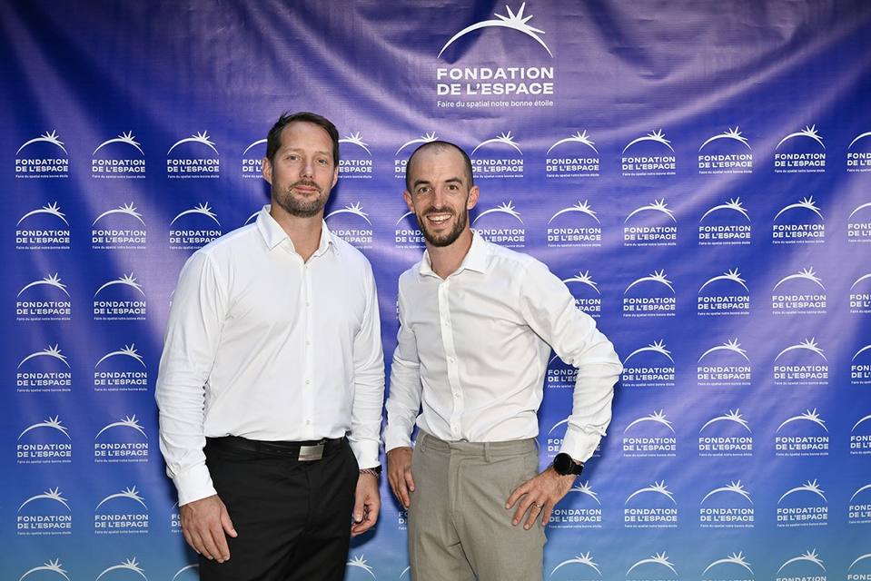 Deux convives en chemise blanche devant le mur aux logos de la Fondation