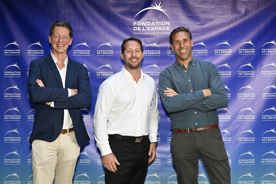 Trois convives souriants devant le mur aux logos de la Fondation de l'Espace