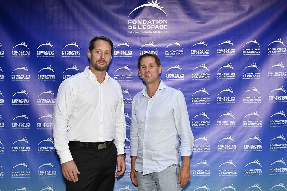 Deux convives en chemise devant le mur aux logos de la Fondation