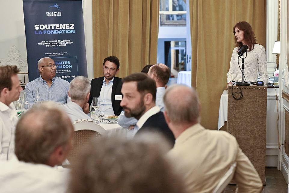 Intervenante au pupitre pendant le dîner, convives attablés devant le kakémono de la Fondation