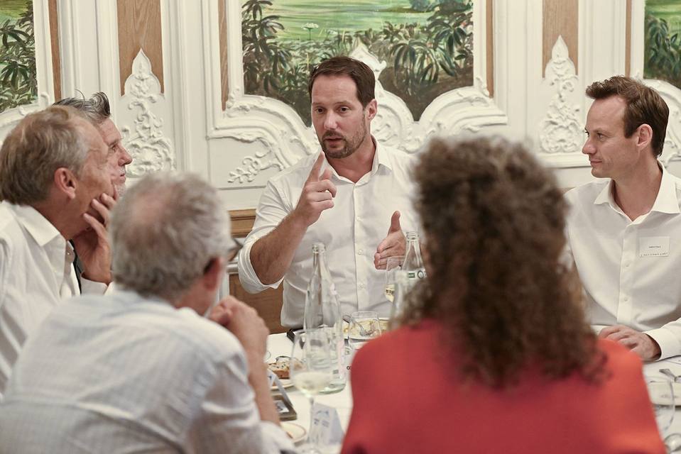 Convive en chemise blanche prenant la parole autour d'une table