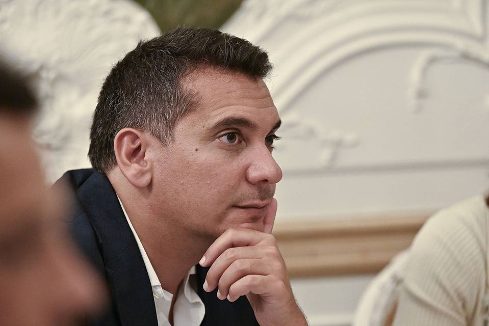 Convive attentif, la main sous le menton, devant les boiseries blanches du salon
