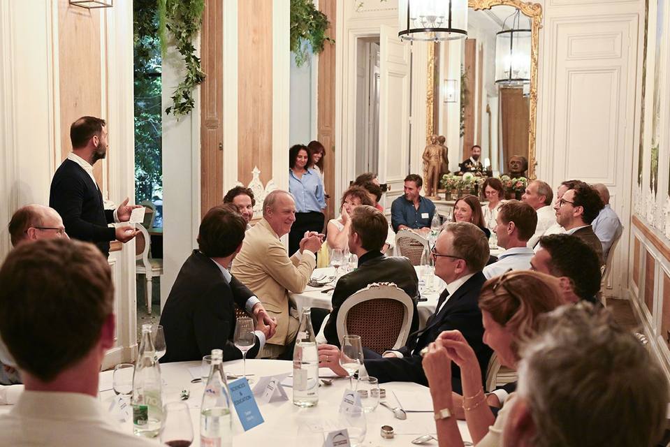 Échanges animés entre convives autour des tables du dîner