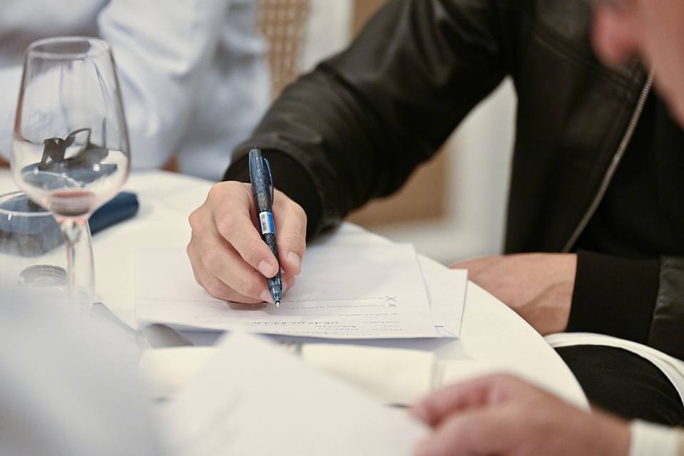 Main d'un convive remplissant un formulaire de soutien à table