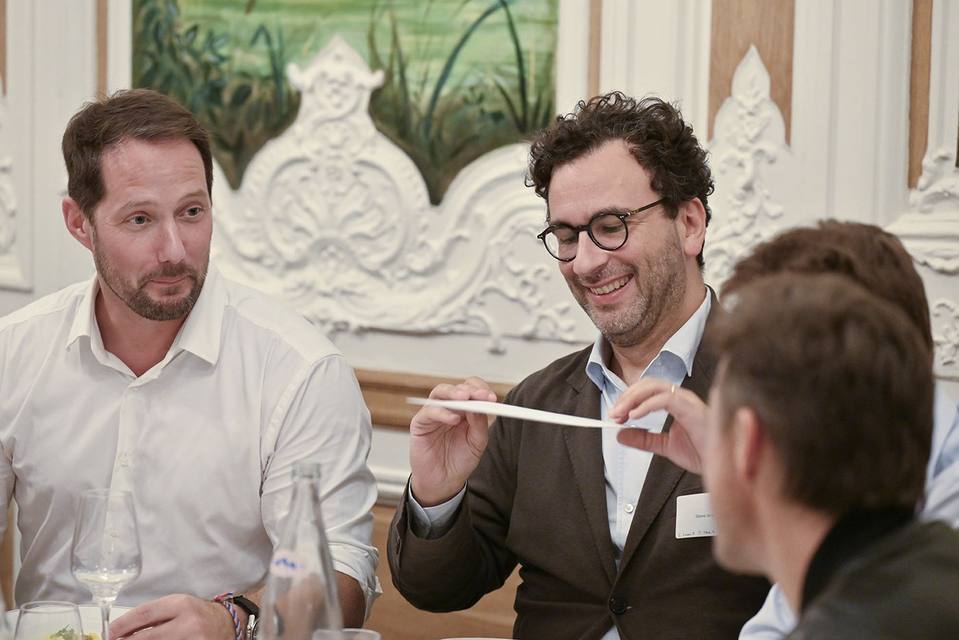 Convives souriants échangeant un document autour de la table