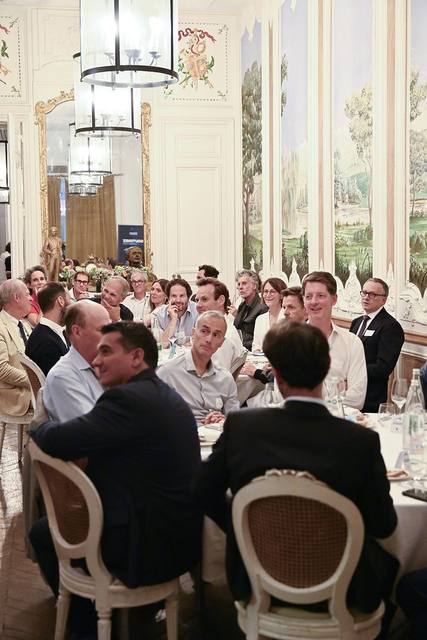 Convives attentifs autour des tables sous les lanternes du salon