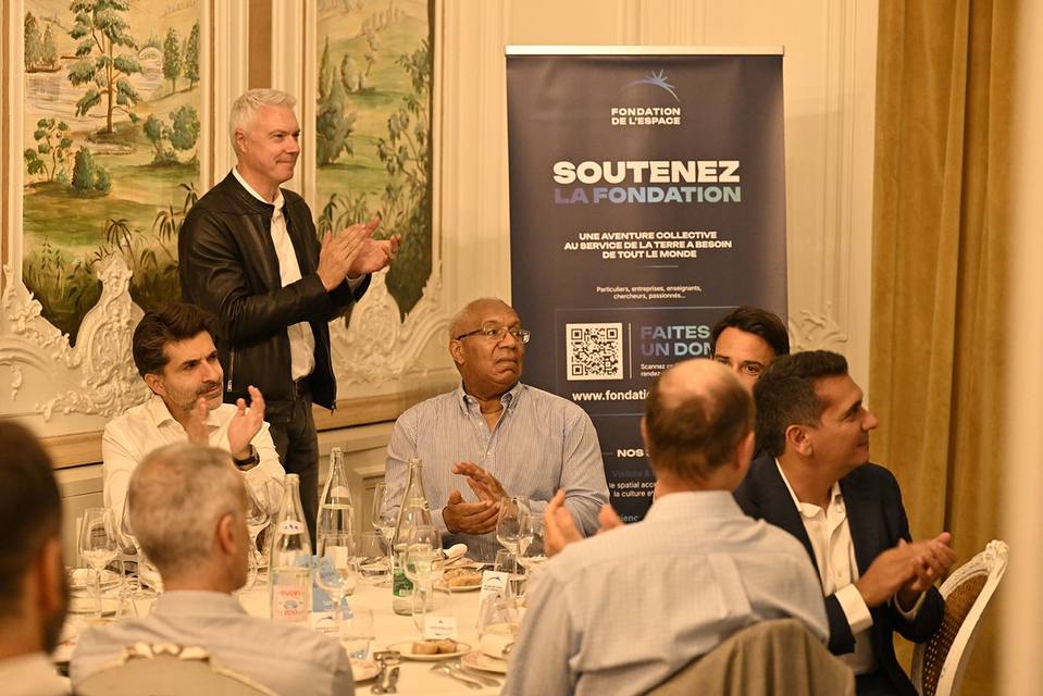 Convives applaudissant devant le kakémono Soutenez la Fondation