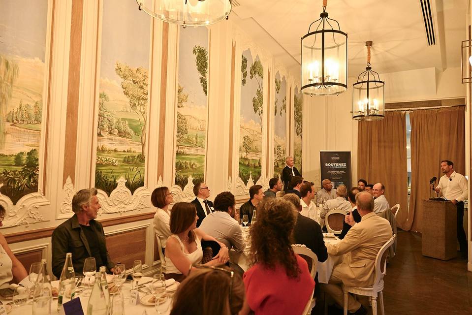 Vue d'ensemble du dîner avec un intervenant au pupitre dans le salon peint