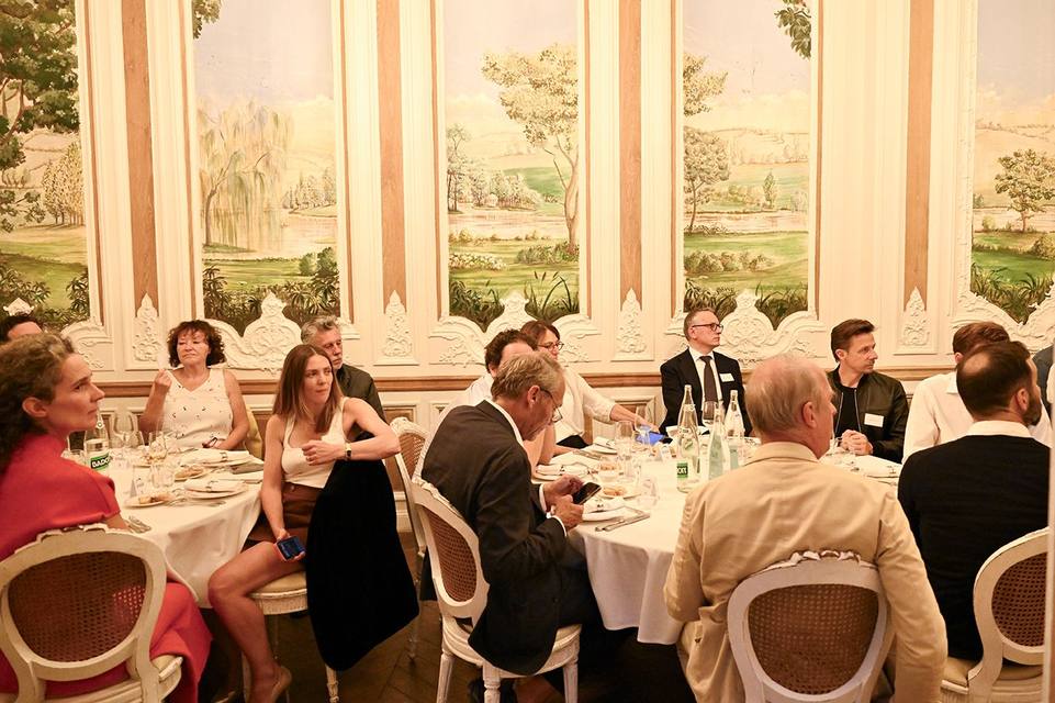 Convives réunis autour des tables devant les fresques du salon
