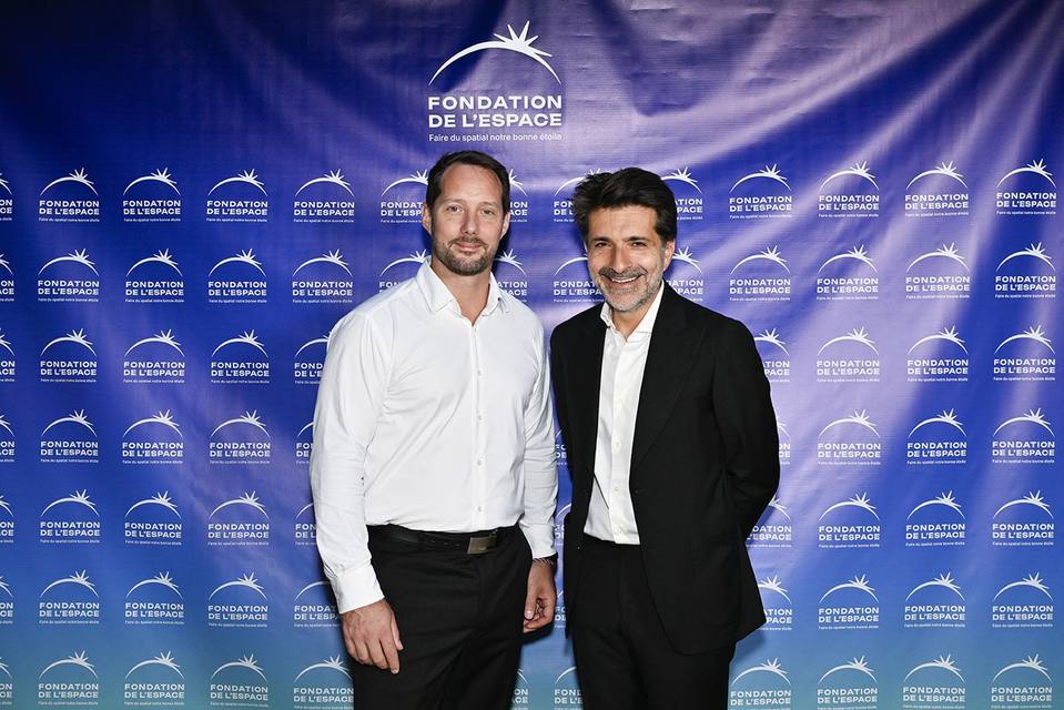 Deux convives posant devant le mur aux logos de la Fondation