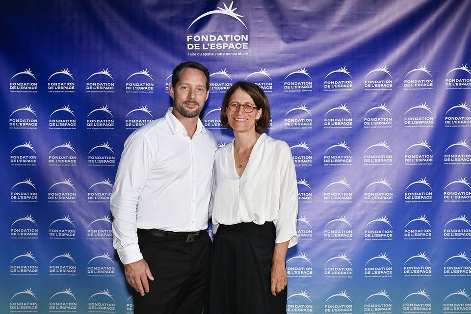 Deux convives côte à côte devant le mur aux logos de la Fondation